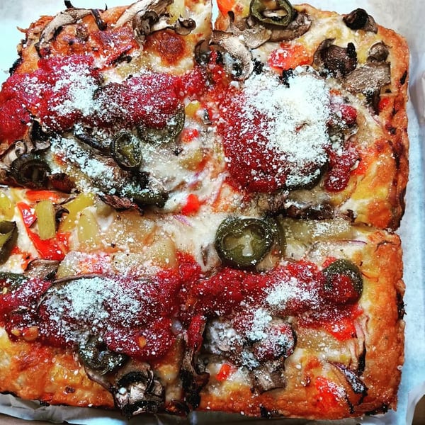 Close-up of a Detroit-style pizza from L.A. Waterfront Pizza, topped with mushrooms, jalapenos, and red sauce.