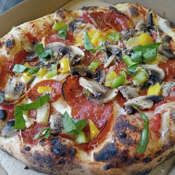 L.A. Waterfront Pizza's pepperoni pizza with mushrooms, bell peppers, and fresh basil in a box.