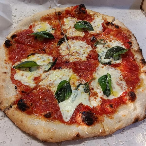 A freshly baked L.A. Waterfront Pizza Margherita, sliced, with vibrant tomato sauce, mozzarella, and basil.